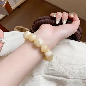 Close-up detail of cream acrylic irregular geometric beaded bracelet worn on a model wrist