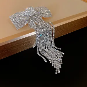 Detailed close-up of a sparkling rhinestone bow hair clip featuring elegant long tassel drops