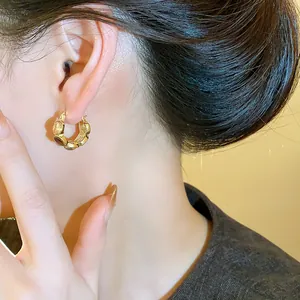 Detailansicht eines vintage goldfarbenen U-förmigen Creolen-Ohrrings mit Harzinlay am Ohr.