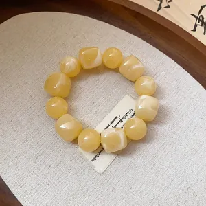 Close-up detail of smooth irregular yellow acrylic beads on a minimalist geometric bracelet