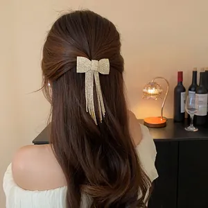 Elegant rhinestone bow hair clip with shimmering tassels shown on wavy brunette hair back view