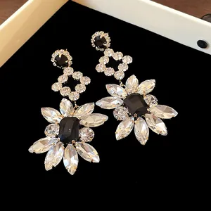 Macro view of silver needle drop earrings with black and clear crystal flower motif