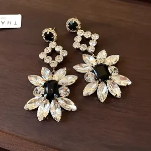 Detailed macro view of silver needle drop earrings with black and clear crystals.