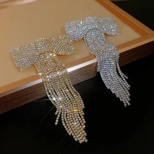 Close-up of sparkling rhinestone bow hair clips with long tassels in gold and silver colors