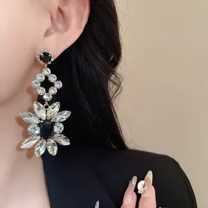 Detail of ornate rhinestone floral dangle earring worn by a model in black blazer.