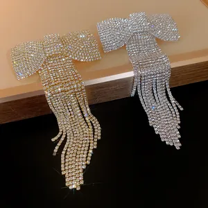 Detailed view of gold and silver rhinestone bow hair clips with long tassels