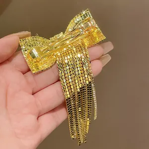 Detail view showing the spring clip mechanism on a golden rhinestone bow hair clip.