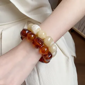 Detail view of acrylic chunky geometric beaded bracelets in amber and cream colors