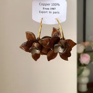 Detaillierte Nahaufnahme von Vintage-Creolen mit braunen Harzblumen auf einer Kupferkarte