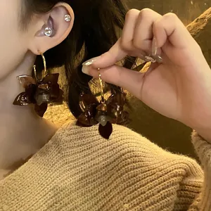 Detail von Vintage-Resin-Blütenohrringen mit goldenen Creolen an einem asiatischen Modell