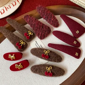 Detail view of plush felt and knitted hair clips with gold B logo and cherry accents.