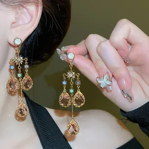 Detailed view of elegant vintage palace style star and crystal drop tassel earrings on a model