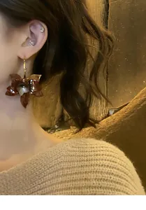 Detailaufnahme von Vintage-Resin-Blumen-Ohrringen mit warmem Design an einem Model.