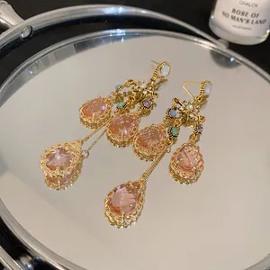 Close-up of French vintage star earrings with pink crystal teardrops on a mirror surface.
