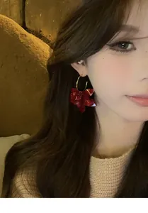 Detailansicht eleganter vintage roter Harzblumen-Ohrhänger getragen von asiatischem Modell