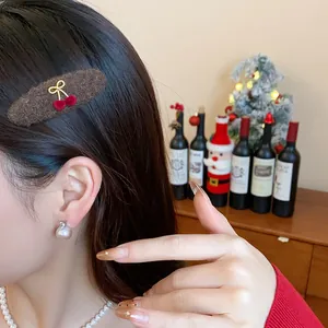 Plush brown hair clip with red cherry bow detail worn by model