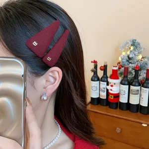 Close-up view of a burgundy velvet triangular BB hair clip with gold letter B decoration