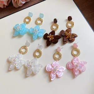 Detailed view of four pairs of resin flower drop earrings in blue, brown, white, and pink