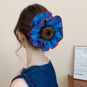 Detailansicht eines blauen Stoff-Haargummis mit roten Rändern an einem Haarknoten
