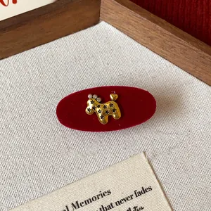 Close-up detail of a red velvet hair clip with elegant golden poodle and star embellishments