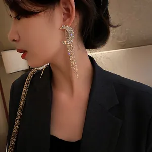Close-up of an Asian model wearing elegant rhinestone crescent moon tassel earrings.