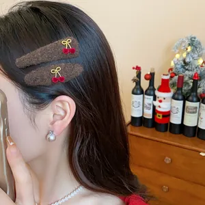 Detailed close-up showing brown plush triangle hair clips with red cherry bow accents