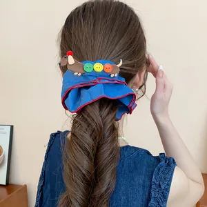 Detailansicht eines blauen Jeans-Haargummis mit süßem Dackel und bunten Knöpfen.