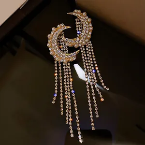 Detail shot of elegant gold crescent moon earrings with long rhinestone tassels and pearls