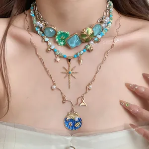 Detailed view of layered bohemian necklace featuring blue shell and star charms on model