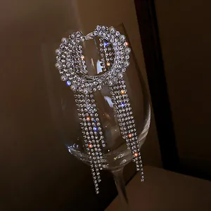 Close-up of sparkling rhinestone tassel earrings with elegant pearl details on glass