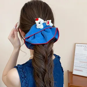 Nahaufnahme eines blauen Stoff-Haargummis mit weißem Bär-Ornament im Haar des Modells