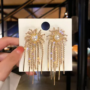 Close-up of elegant gold-toned rhinestone tassel earrings featuring a central pearl inlay detail