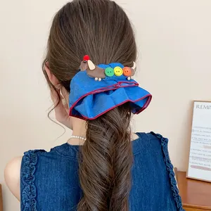 Detail eines blauen Denim-Haargummis mit Dackel- und Knopf-Anhänger für Damen
