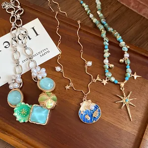 Detailed view of bohemian necklaces with pearls, seashells, stars, and beads on wooden tray