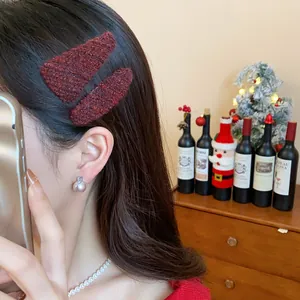 Close-up of burgundy textured fabric triangle hair clips worn on long dark hair.