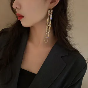 Close-up of elegant long gold tassel earrings with rhinestones worn by a model