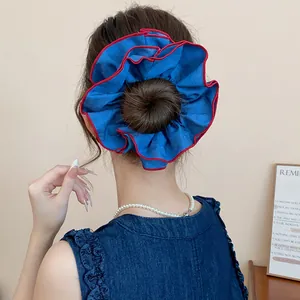 Detailansicht eines doppellagigen blauen Stoff-Haargummis mit rotem Rand in einem Dutt.