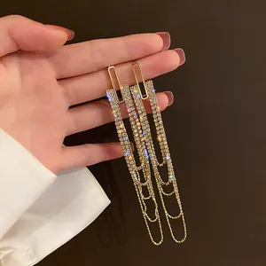 Close-up of gold-tone long tassel earrings with sparkling rhinestones and chains