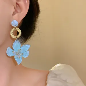 Detailed close-up view of elegant light blue resin flower drop earrings on a model