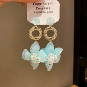 Detailed view of light blue resin flower earrings with textured gold hoops