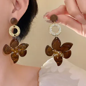 Close-up view of amber resin flower drop earrings with gold textured rings on a model.