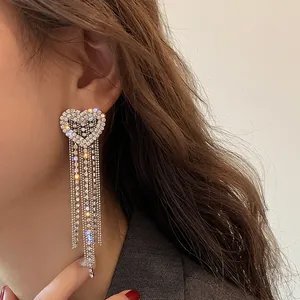 Close-up detail of silver tassel earrings with sparkling heart-shaped diamond studs