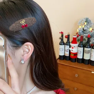 Close-up of a festive brown plush hair clip with red cherry motif worn on a model's hair.