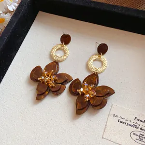 Detail view of dark brown resin flower earrings with gold textured circular links