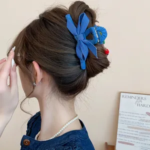 Detailaufnahme einer blauen Haarklammer mit Jeansschleife an einem Dutt für Damen