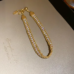 Detailed view of gold-tone bracelet featuring twisted chain and sparkling rhinestones.