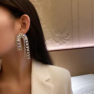 Detailed close-up of sparkling rhinestone tassel earrings worn by a model in a blazer.