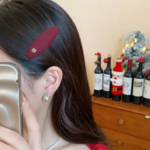 Close-up of a burgundy knit BB hair clip with B metal detail worn on hair.
