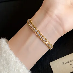 Close-up view of an elegant gold twisted chain bracelet with sparkling stones on wrist.