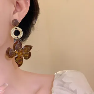 Detailed close-up view of elegant dark brown resin flower pendant earrings worn by a model
